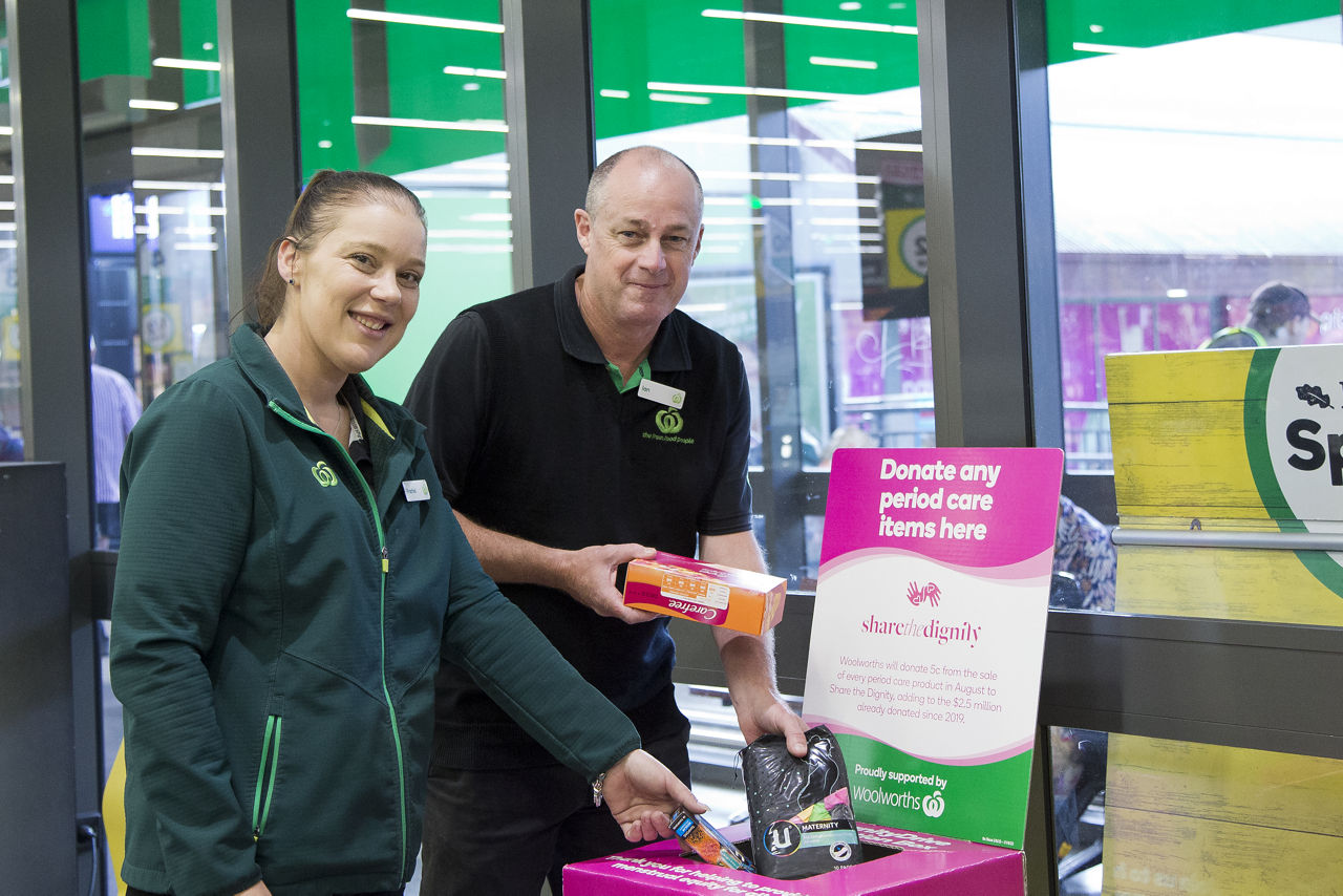 Two store team members holding period products for donation