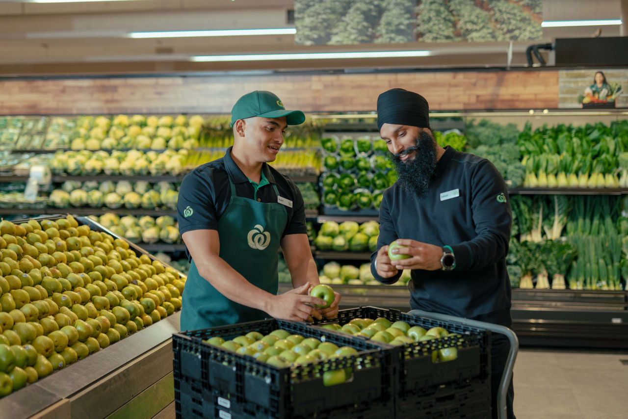 Two employees working together to stock the shelf at the supermarket