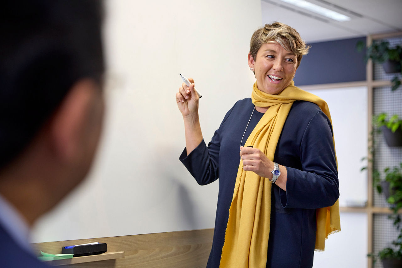 A woman standing and writing on the white board with a marker