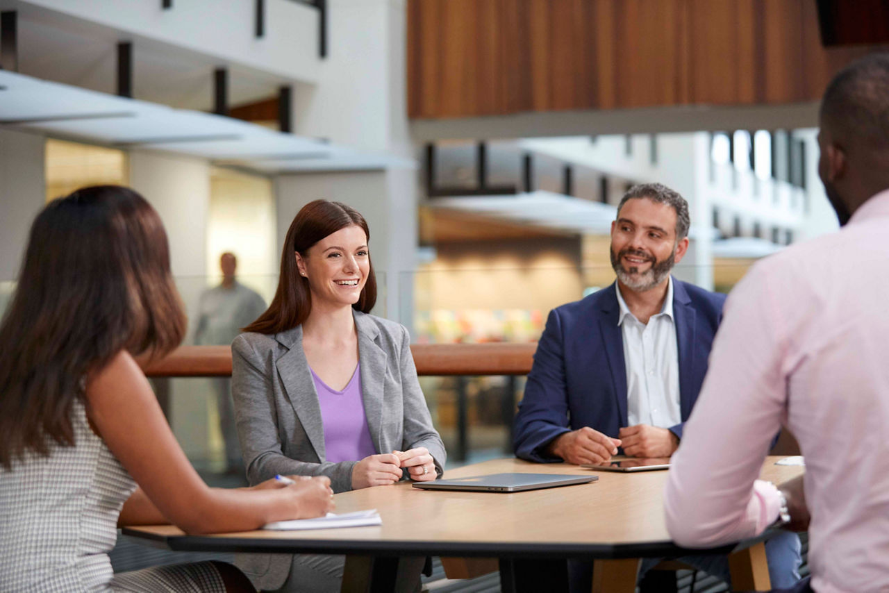 A group of staff members talking at the table in the office