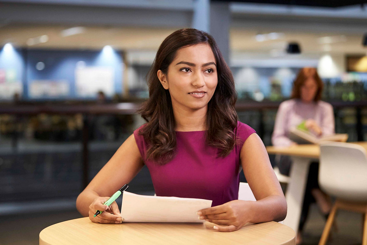 A woman in an office sitting at a desk and looking at paper work