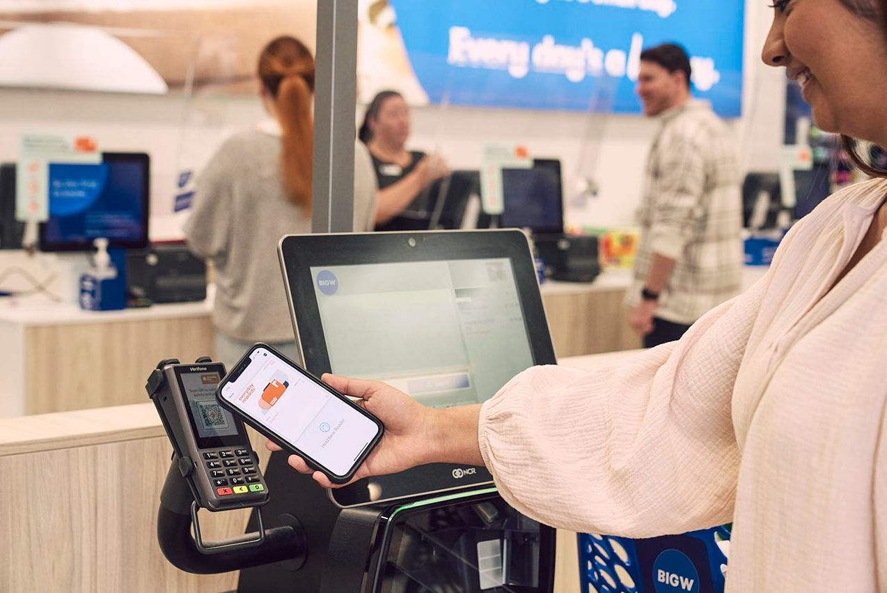 A woman using her phone to scan her Everyday Rewards card at the checkout